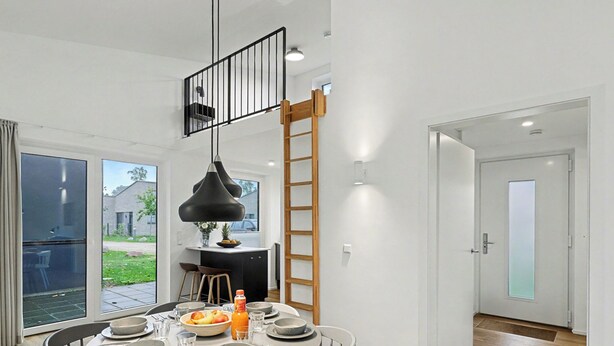 A modern dining area with a round table set for four, a black pendant light, and a view of the outdoors. - Dünenblick 165 (Seenähe) by Interhome (Lembruch)