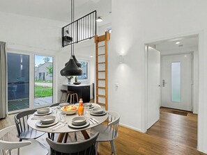 Een moderne eetruimte met een ronde tafel voor vier personen, een zwarte hanglamp en uitzicht op de omgeving.