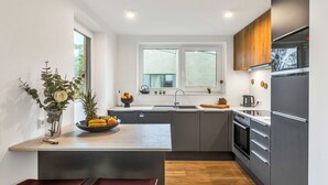 A modern kitchen with a central island, dark cabinetry, and a window above the sink. - Dünenblick 165 (Seenähe) by Interhome (Lembruch)