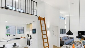 Eine moderne Küche mit weißen Schränken, einer Holzleiter und einem Essbereich mit Tisch für zwei Personen.