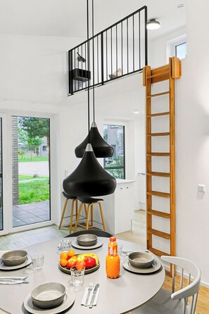 A modern dining area with a round table, black chairs, and a black pendant light. - Favola 236 by Interhome (Lembruch)