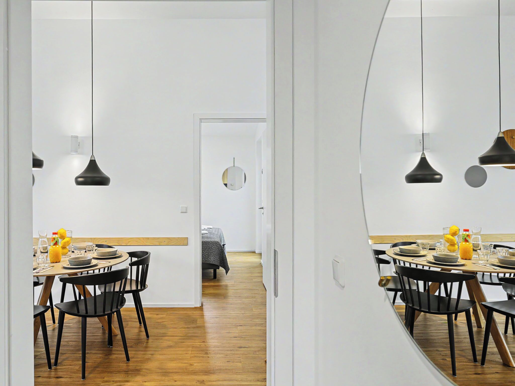A modern dining area with black chairs, a wooden table, and black pendant lights.