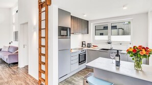 A modern kitchen with stainless steel appliances, a wooden ladder, and a dining area with a vase of flowers. - Zwischen den Hügeln 153 by Interhome (Lembruch)