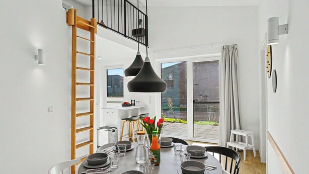 A modern dining area with a round table, black chairs, and a black pendant light.