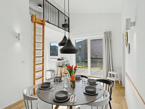 Zona pranzo moderna con tavolo rotondo, sedie nere e lampada a sospensione nera.