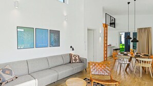 A modern living room with a gray sofa, a dining area with a wooden table and chairs, and a staircase leading to an upper level. - Küstenzauber 282 by Interhome (Lembruch)