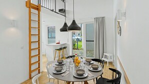 Un'area pranzo moderna con un tavolo rotondo apparecchiato per quattro persone, una scala in legno e vista sull'esterno.