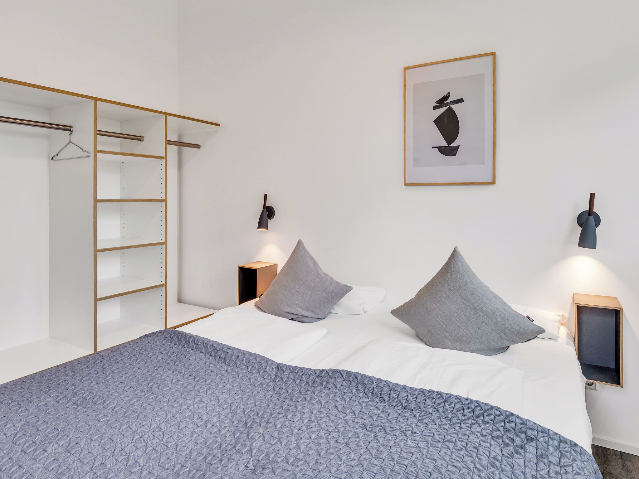 Ein Schlafzimmer mit einem Bett, zwei Nachttischen, einem Kleiderschrank und einem Wandbild.
