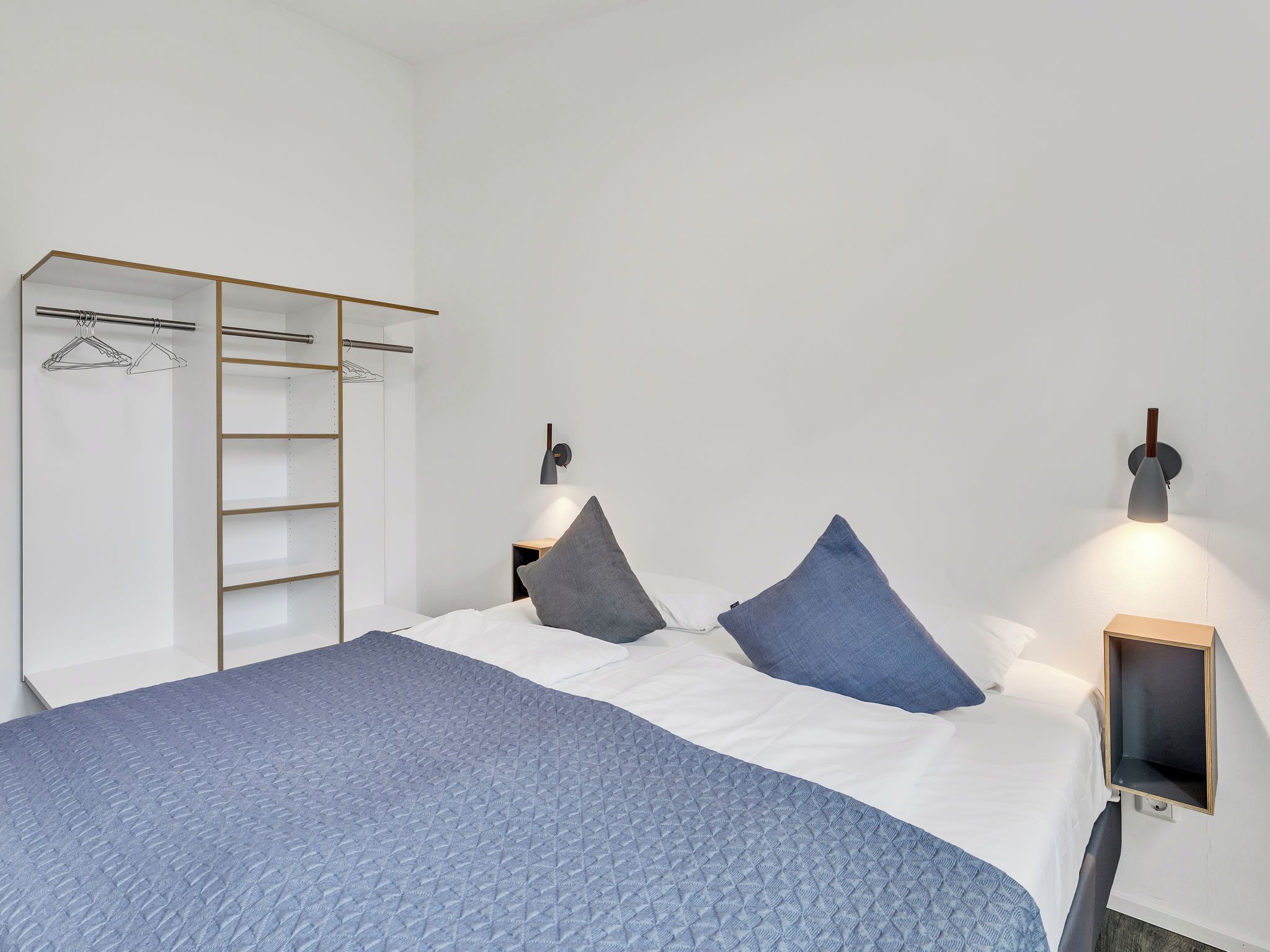 Ein Schlafzimmer mit einem Bett, einem Kleiderschrank und zwei Wandleuchten.