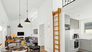 A modern kitchen with a built-in oven, a dining area with a round table and chairs, and a living room with a sofa and a TV. - Goldfisch 191 (Seenähe) by Interhome (Lembruch)