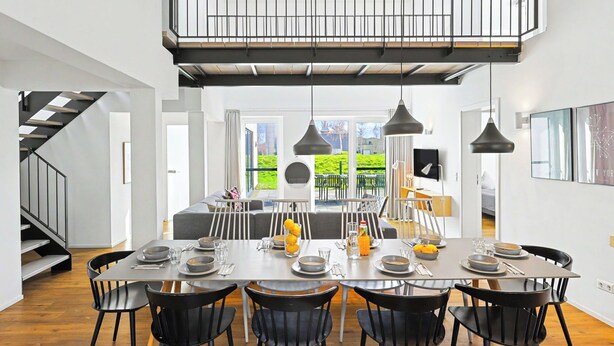 A modern dining area with a high ceiling, black chairs, and a central table set for four. - Dümmersee Lodge 147 by Interhome (Lembruch)