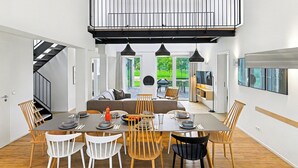 A modern dining area with a large table, multiple chairs, and pendant lighting.