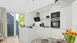 Una cocina moderna con una isla central, una mesa de comedor con sillas y vistas al exterior.