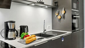 Eine moderne Küche mit Dunstabzugshaube aus Edelstahl, einer Kaffeemaschine, einem Wasserkocher, einer Spüle und einem Kühlschrank.