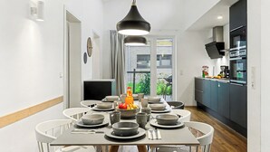 Eine moderne Küche mit dunklen Schränken, einem großen Fenster und einem Essbereich mit Tisch für vier Personen.