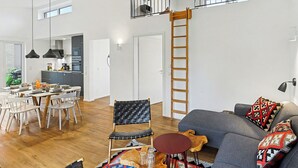 Ein großzügiger Wohnbereich mit Esstisch, Stühlen, einer Couch und einer Treppe zu einem Balkon.