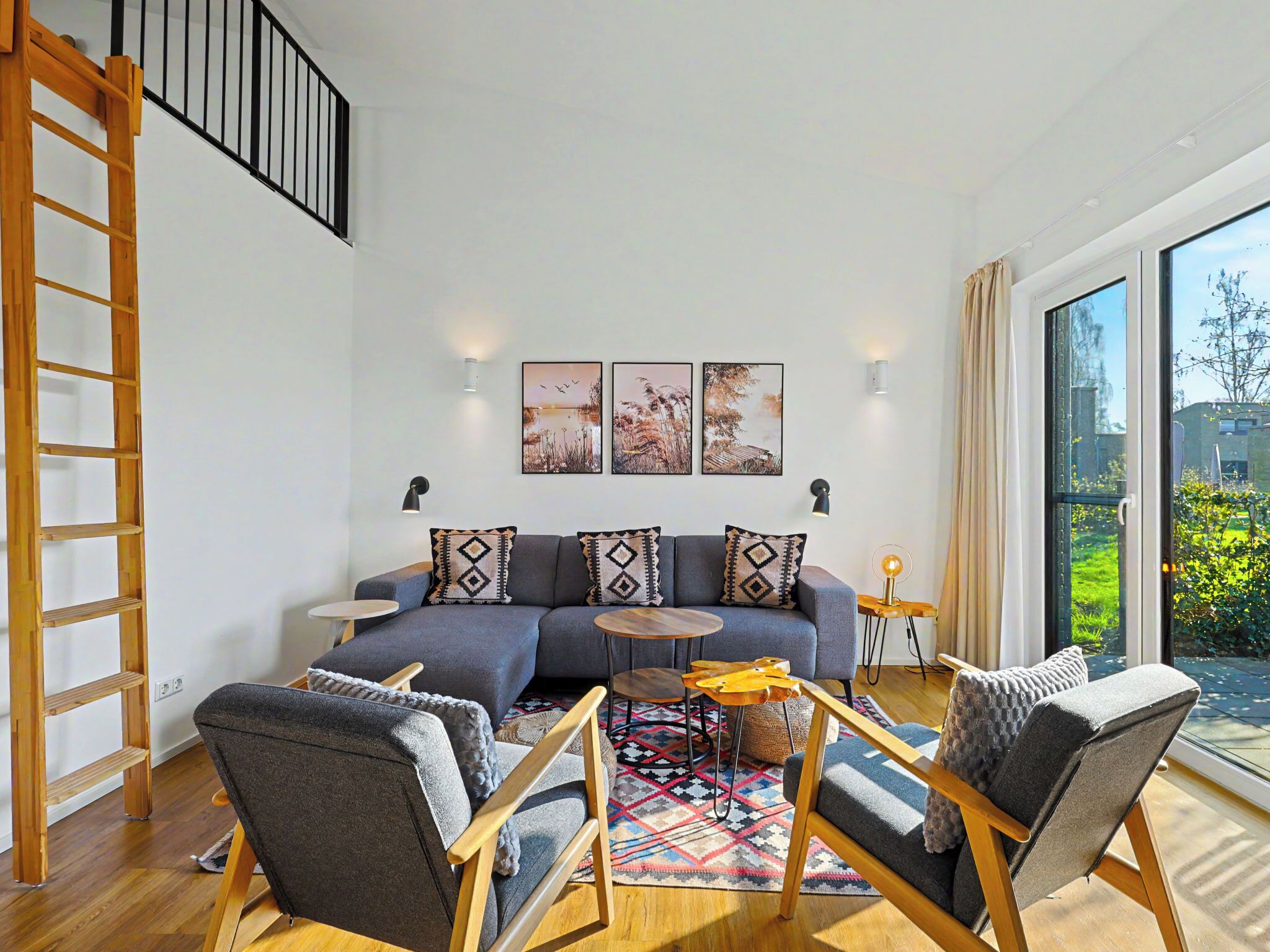 Een moderne woonkamer met een bank, twee fauteuils, een salontafel en een houten ladder.