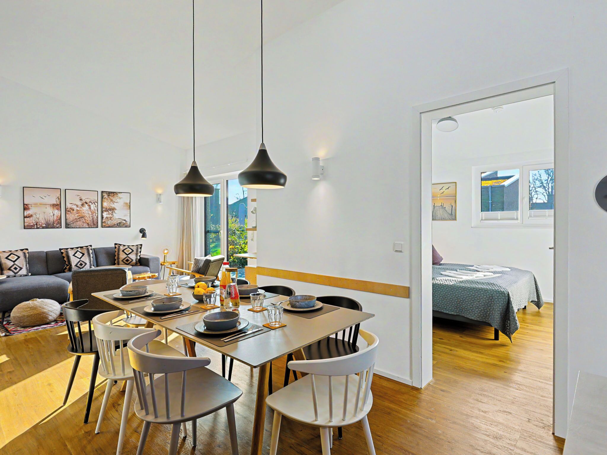 A dining area with a table set for four, a sofa, and a bed in the adjacent room.
