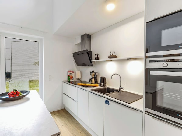 A compact kitchen with white cabinetry, a built-in oven, a sink, and a small countertop.