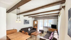 Ein gemütliches Wohnzimmer mit einem Holzesstisch, zwei Sofas und einem Fernseher.