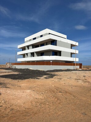 Ein modernes, mehrgeschossiges Gebäude mit flachem Dach, großen Fenstern und einer Holzfassade.