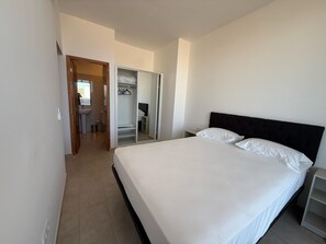 A bedroom with a large bed, a wardrobe, and a bathroom visible through an open door. - Joli Beach House - Superb Santa Maria Apartment With Breathtaking Views (Sal)