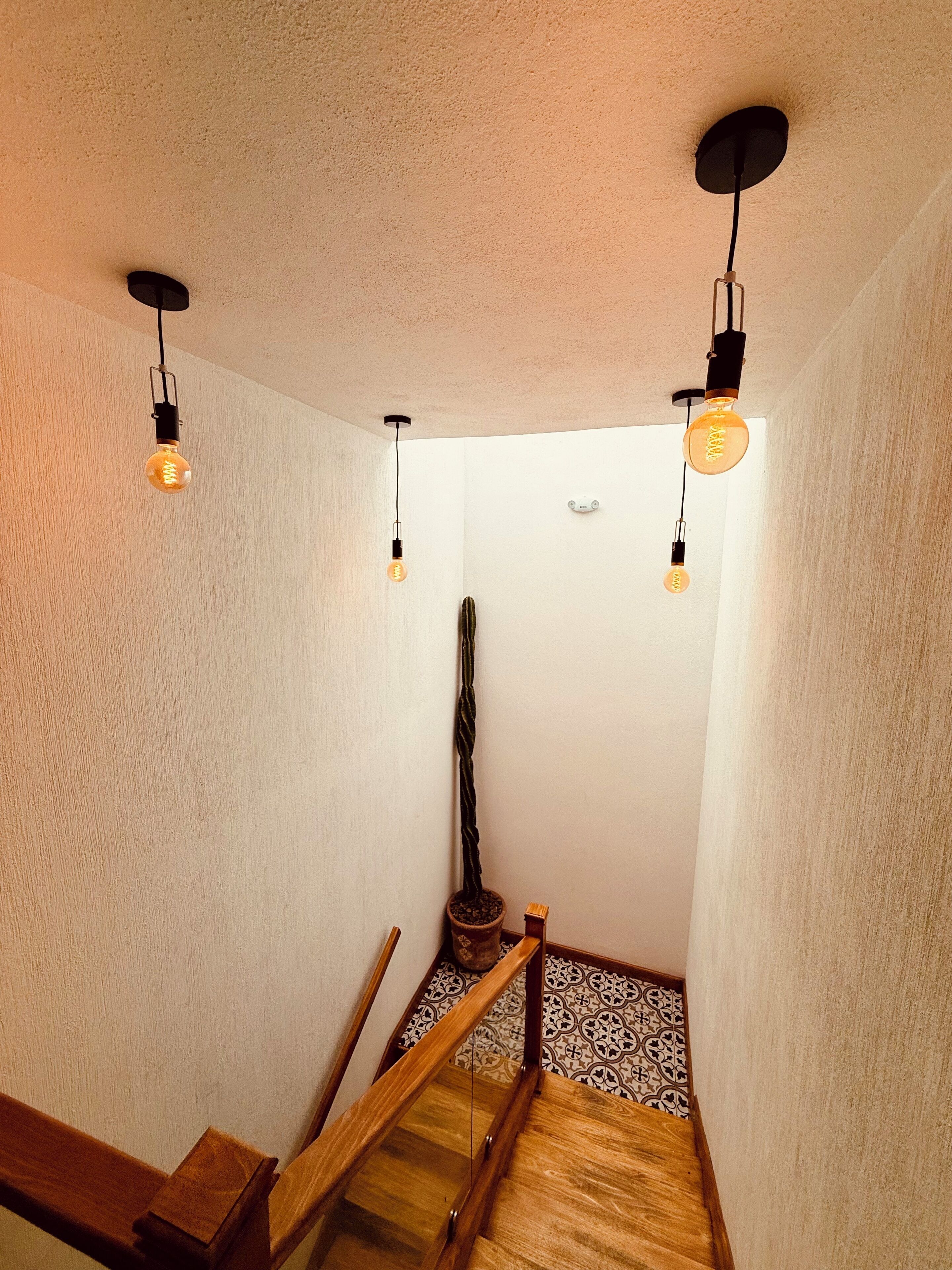 Una escalera estrecha con barandillas de madera y baldosas de suelo con diseño.