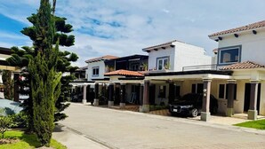 A residential street with modern houses, a central tree, and a paved road. - Casa Quetzal Xela, ideal house for a comfortable stay and central location. (Quetzaltenango)