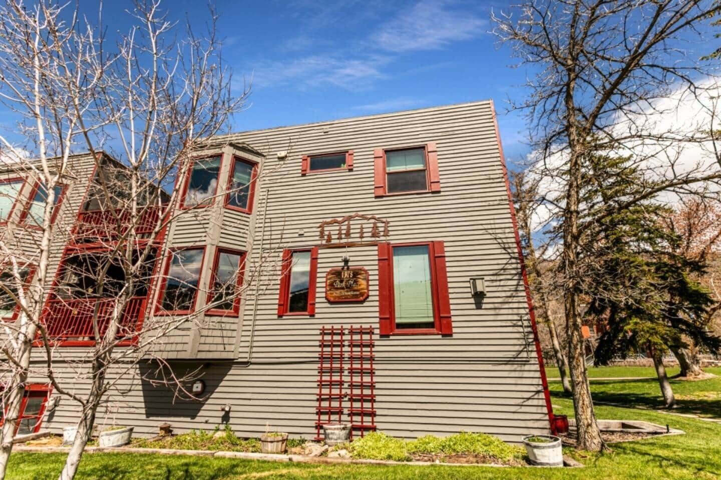 A two-story building with a sloped roof, multiple windows with red shutters, and a small porch area.