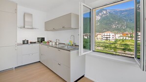 Una cocina moderna con armarios blancos y una ventana con vista a un paisaje montañoso.
