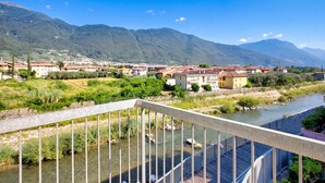 Un río con un puente, edificios y montañas al fondo.