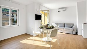A modern living space with a dining area, a sofa, and a TV. - Ulivo Bike & River Apartment, Arco, Italy (Arco)