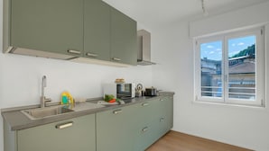 A modern kitchen with a sink, cabinets, and a window with a view of buildings. - Ulivo Bike & River Apartment, Arco, Italy (Arco)