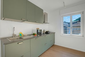 Una cocina moderna con un lavamanos, armarios y un ventanal con vistas a edificios.