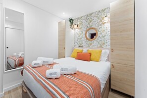 Quarto de hotel com cama, espelho, luminária fixada na parede e parede revestida de madeira.