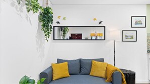 A living room with a grey sofa, yellow cushions, a hanging plant, a mirror, and framed pictures on the wall. - GuestReady - Porto's relaxing nook (Porto)
