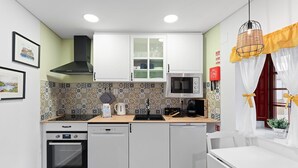 A compact kitchen with white cabinets, a microwave, a coffee maker, and a dishwasher. - GuestReady - Porto's relaxing nook (Porto)