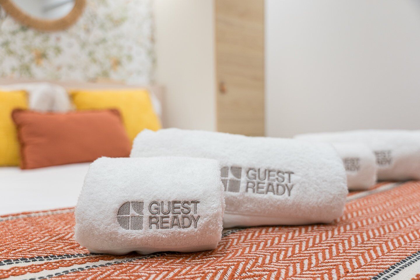 Ett hotellrum med en snyggt bäddad säng, en mönstrad matta och en vägg med en dekorativ spegel.