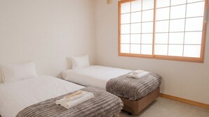 A hotel room with two beds, a large window, and a carpeted floor. - THE GAKUSUI - Hostel  (Hakuba)