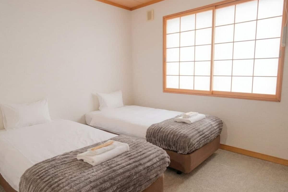Une chambre d’hôtel avec deux lits, une grande fenêtre et un sol recouvert de moquette.