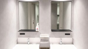 A modern bathroom with two sinks, a mirror above each, and a towel dispenser in the center. - THE GAKUSUI - Hostel  (Hakuba)