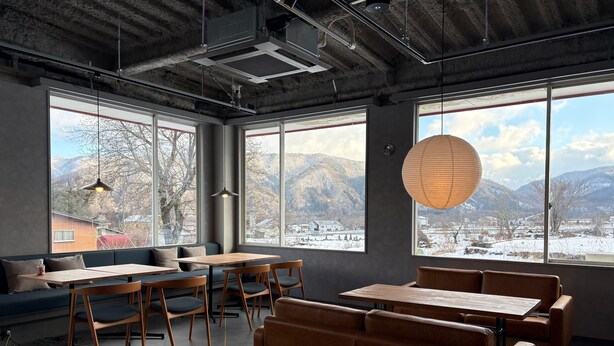 A modern interior with large windows, wooden furniture, and a view of snow-covered mountains. - THE GAKUSUI - Hostel  (Hakuba)