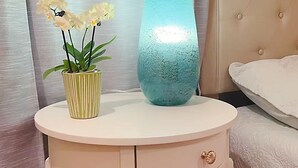 A round white nightstand with a drawer, a blue vase, and a potted plant with yellow flowers. - Serene cottage with AC in Milpitas - 2 bedrooms available (Milpitas)