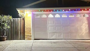 A garage with a white door, adorned with colorful string lights. - Serene cottage with AC in Milpitas - 2 bedrooms available (Milpitas)