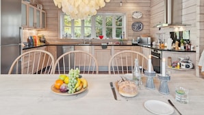 Een moderne keuken met houten kastjes, een groot raam en een eethoek met een schaal fruit.