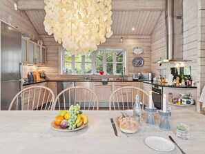 A modern kitchen with wooden cabinets, a large window, and a dining area with a fruit bowl. - "Fatiha" - 800m from the sea by Interhome (Højby)
