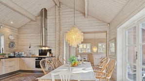 Een ruime keuken met een grote eettafel, houten stoelen en een hanglamp.