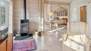 Een gezellig houten huisje van binnen, met een houtkachel, een eethoek en een keuken.