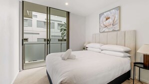 Una camera da letto moderna con un letto grande, una porta vetrata che dà su uno spazio all'aperto e un quadro floreale appeso alla parete.