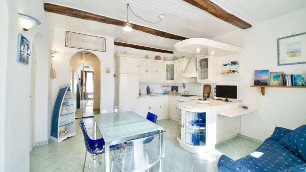 Een ruimtelijk ingerichte leefruimte met een eethoek, kitchenette en een bank.